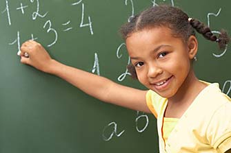 Smiling student solving math equations on chalkboard.